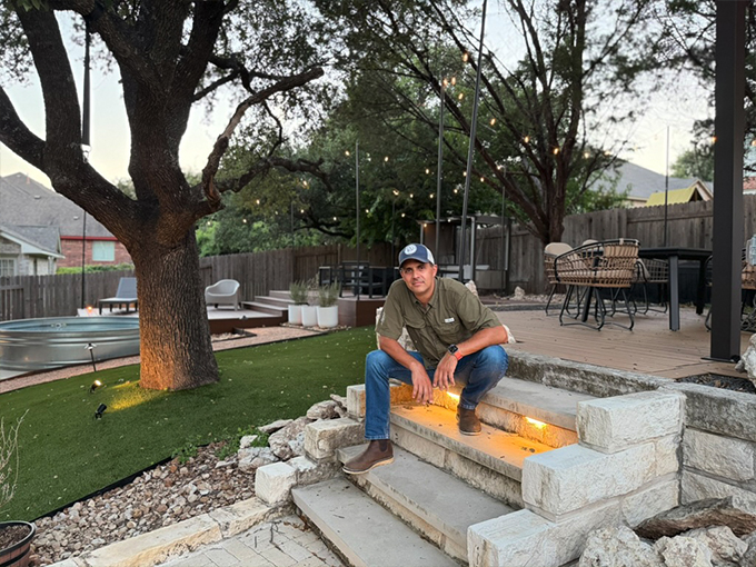 Diego Dessens, landscape architect, next to a completed outdoor kitchen at sunset in Austin TX